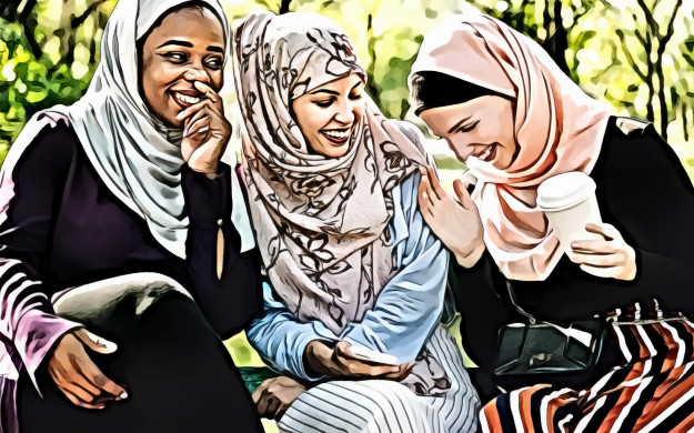 Women Laughing and Dressed in Hijabs Sitting Next to Each Other