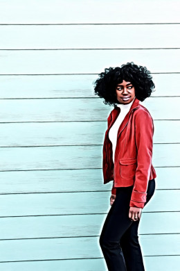 Woman in Red Blazer Standing Beside Light-blue Wall Looking Sideways