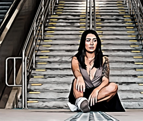 Woman Sitting on the Ground with Gray Concrete Stairs and Escalators in the Background