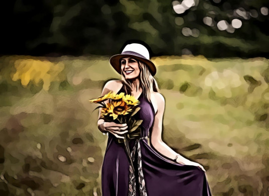 Photo of smiling woman in purple dress holding sunflower bouquet