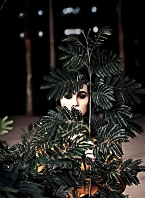 Woman standing behind green plant