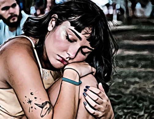 Tattooed woman with her eyes closed resting on her knee