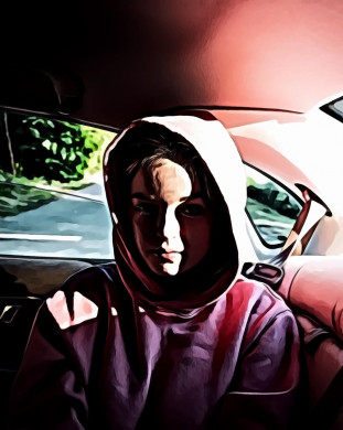 Woman sitting inside vehicle wearing a hoodie