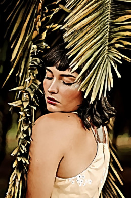 Woman standing under palm leafs with her eyes closed