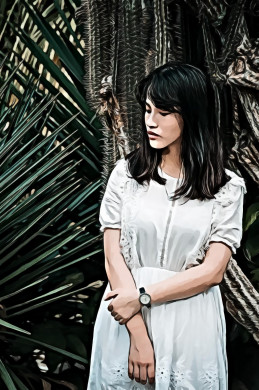 Woman wearing a teal half sleeved dress standing beside green plant